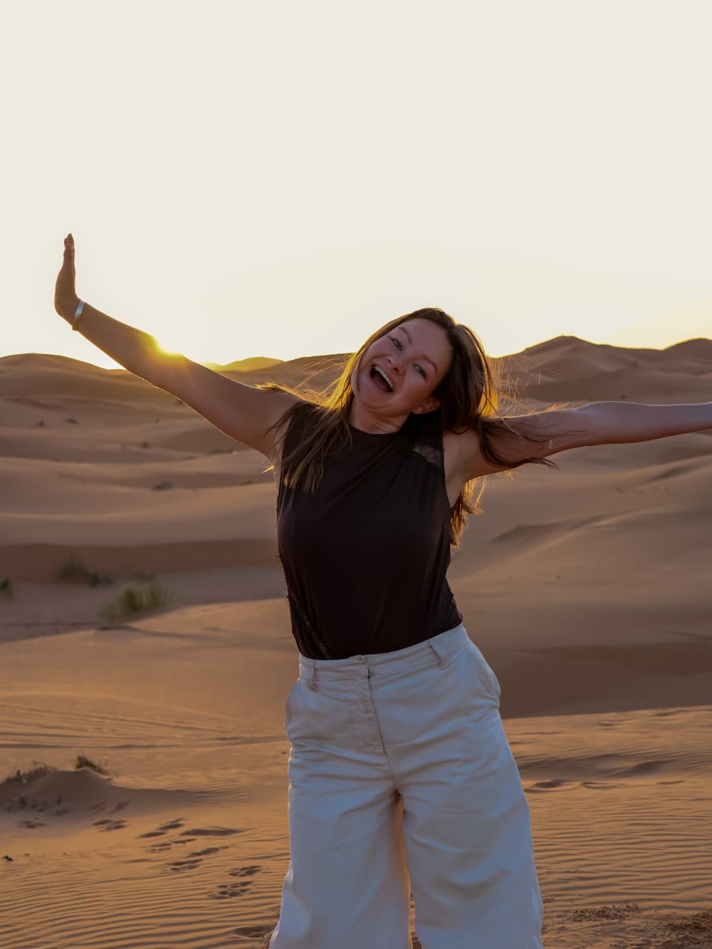 Lotte Boersma met gespreide armen, lachend in de woestijn